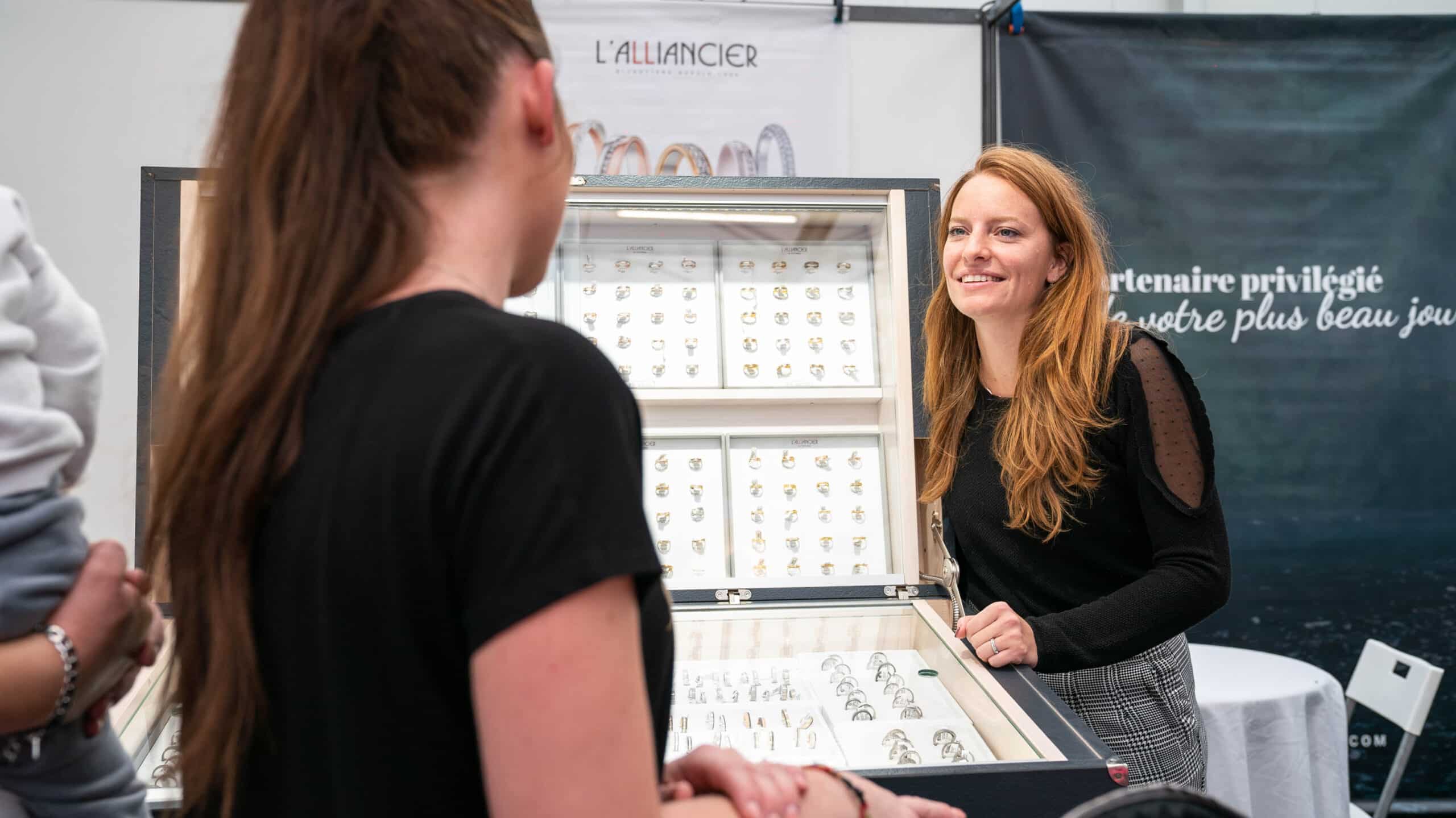 A woman browsing a jewelry stall at an outdoor market, showcasing luxury items under a tent.