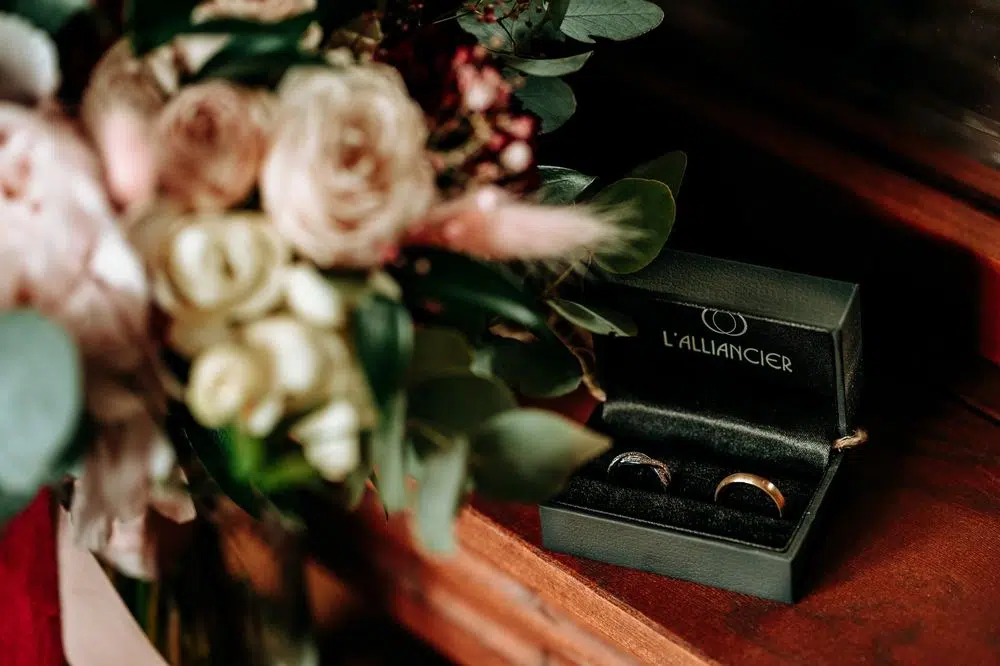 A pair of gold rings inside a red velvet box surrounded by rose petals, symbolizing romance.