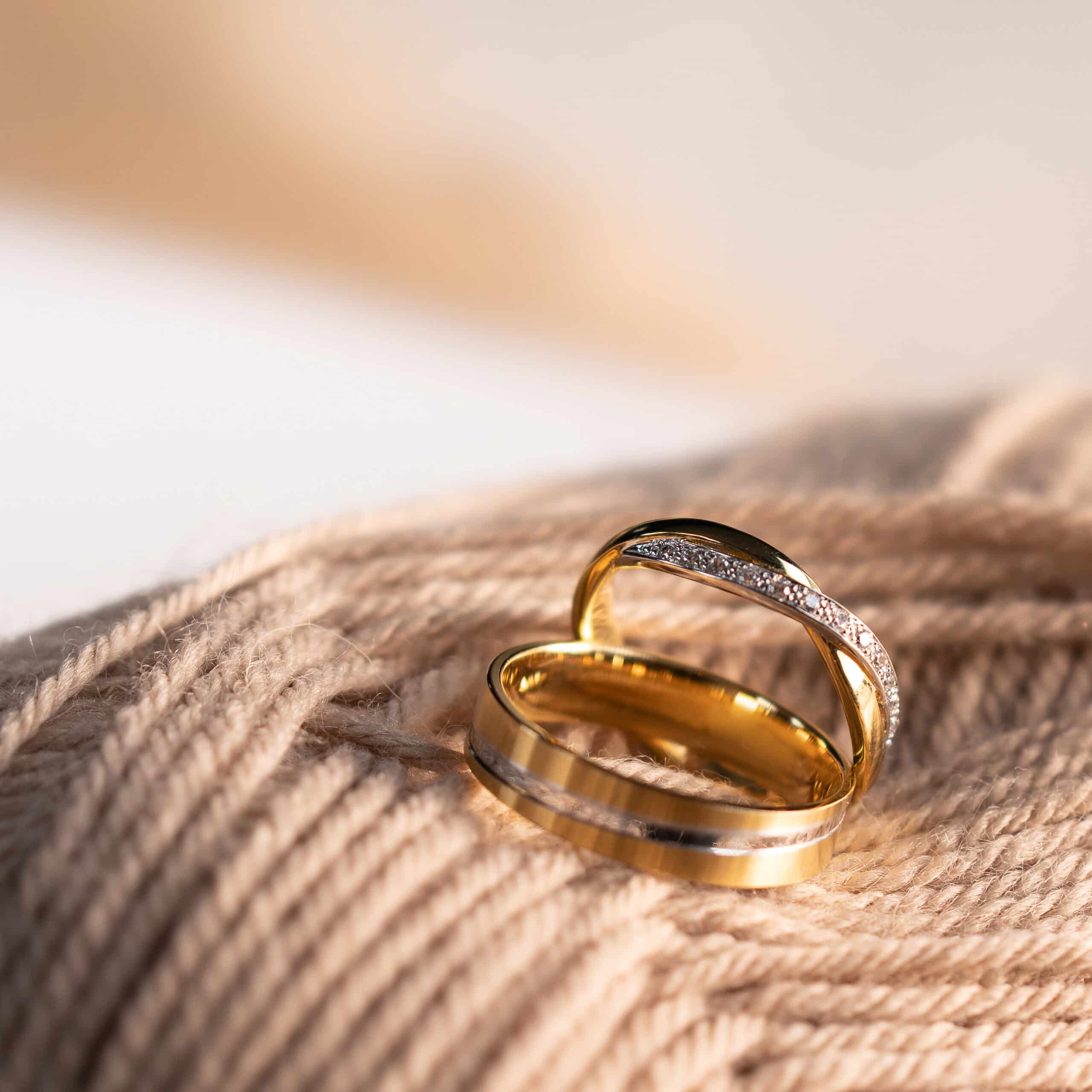 A close-up photo of a couple's hands showing wedding and engagement rings.