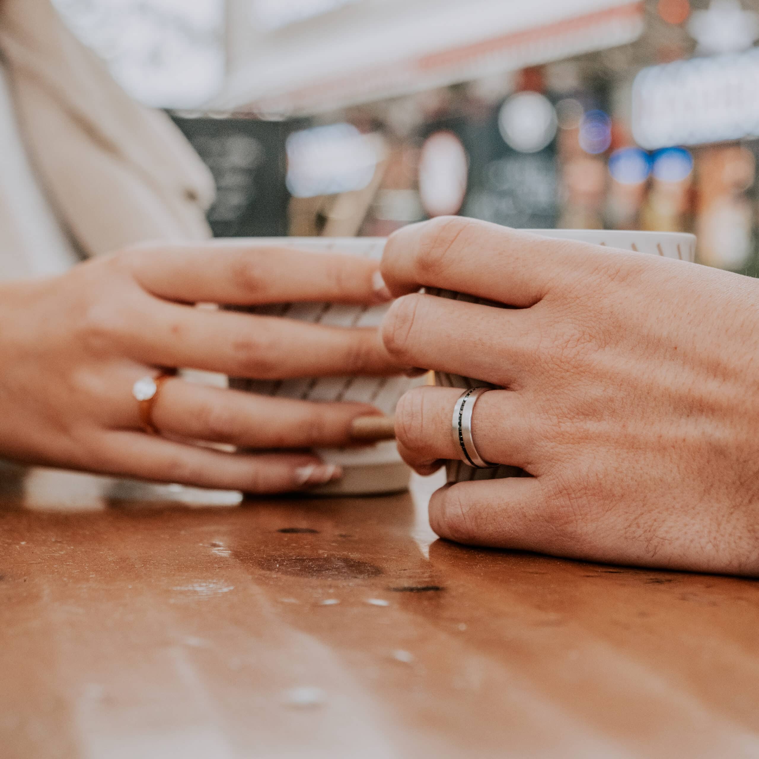Close-up of a couple holding hands, showcasing an elegant engagement ring, symbolizing love and commitment.
